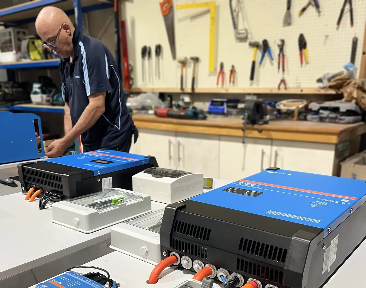 Off-Grid Energy technician setting up Victron inverters in the workshop